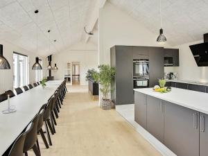 een grote keuken met een lang aanrecht en stoelen bij 30 person holiday home in Bogense in Bogense