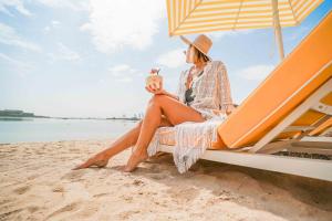 a woman sitting on a beach with an umbrella at Andaz Dubai The Palm, By Hyatt in Dubai +170 photos
