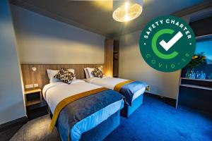 two beds in a hotel room with a green sign at The Old Quarter Townhouse in Limerick