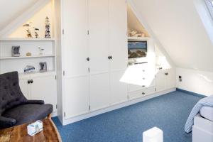 a attic room with white cabinets and a chair at Carlotta s Beachroom in List