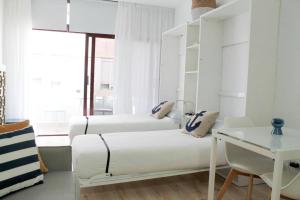 ein weißes Schlafzimmer mit 2 Betten und einem Schreibtisch in der Unterkunft VV Loft Canteras Gran Playa "by henrypole home" in Las Palmas de Gran Canaria