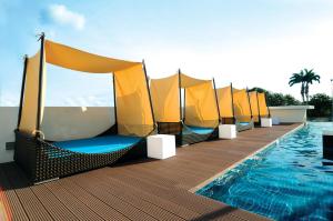 a row of hammocks on a deck next to a swimming pool at Kings Green Hotel City Centre Melaka in Melaka