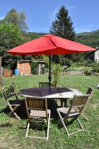 een tafel met een rode parasol en twee stoelen bij Gite du Carbounet et la Grange de Lou in Siguer