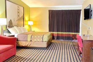 a hotel room with a bed and a red couch at Super 8 by Wyndham Rocky Mount I-95 EXIT 145 in Battleboro