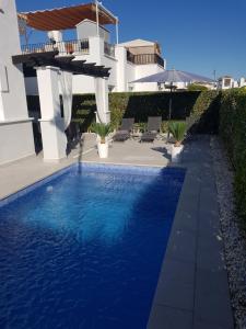 a blue swimming pool in front of a house at Villa mit privatem Pool, zentrumsnah in Roldán