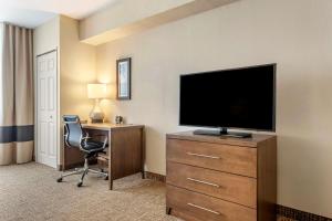 a hotel room with a television and a desk with a chair at Comfort Suites Maingate East in Orlando