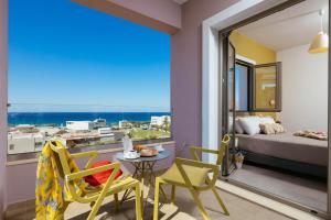 a room with a balcony with a bed and a table and chairs at Sea View Luxury Apartments in Plakias