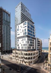 un edificio blanco alto frente al océano en Renoma, en Tel Aviv