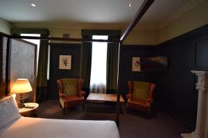 a hotel room with a bed and two chairs at The Globe in Warwick