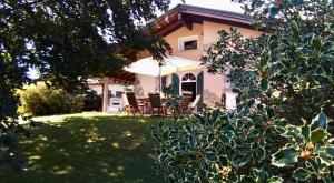 ein Haus mit einem Regenschirm und Stühlen im Hof in der Unterkunft Al Chiar di Luna B&B Valtellina in Chiuro