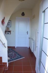 um corredor com uma porta branca e um piso de azulejo vermelho em Ferienwohnung Auszeit Waxweiler em Waxweiler