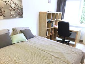 een slaapkamer met een bed, een bureau en een stoel bij Knus tuin-appartement vlakbij Nijmegen voor 2 personen in Molenhoek