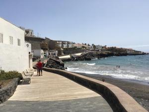 ポリス・デ・アボナにあるLeuchtturmterrasseのビーチの横にある木製の遊歩道に立っている男性