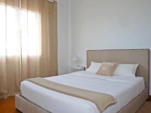 a bedroom with a large white bed with a window at Home for Travellers ll in Ponta Delgada