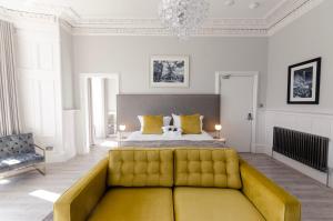 a bedroom with a bed and a yellow couch at Sweeney Apartments & Rooms in Motherwell