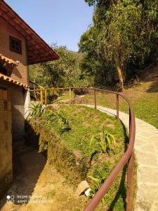 uma grade de metal ao lado de um caminho ao lado de uma casa em Chale Truta da Floresta 2 em Visconde de Mauá