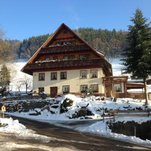 a large wooden house with snow in front of it at Bartleshof in Wolfach