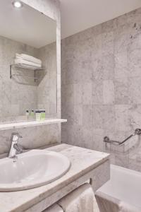 a white bathroom with a sink and a tub at Eurostars Indautxu in Bilbao
