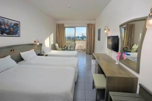 a hotel room with two beds and a television at Nissiana Hotel & Bungalows in Ayia Napa