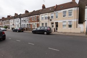 un coche aparcado al lado de una calle con casas en Tooting Broadway Studios & Rooms by PrimeCityHosts, en Londres