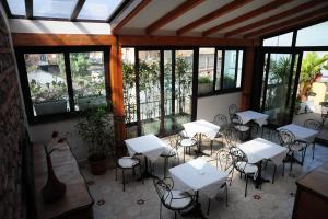 Un restaurante con mesas y sillas blancas y ventanas. en Sangiuliano114 B&B, en Catania