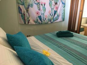 1 cama con almohadas azules y una pintura en la pared en Una Araucaria sul mare, en San Giorgio
