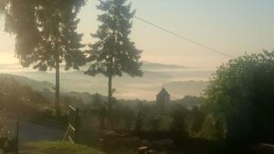 una vista nebbiosa di una collina con alberi e una chiesa di Zlatica a Kalnik