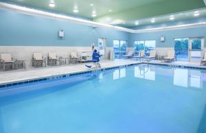 a swimming pool with tables and chairs in a building at Holiday Inn Express & Suites - Lexington W - Versailles, an IHG Hotel in Versailles