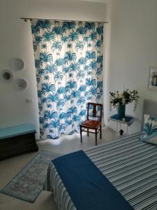 um quarto com uma cama, uma cadeira e uma cortina em Casa Ferreri em Santa Ninfa