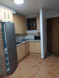 eine Küche mit einem Kühlschrank aus Edelstahl und Holzschränken in der Unterkunft Alojamiento Fuentes in Arroyo Frio