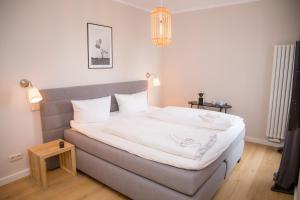 ein Schlafzimmer mit einem großen Bett mit weißer Bettwäsche in der Unterkunft FerienDüne "Riedensee" in Kühlungsborn