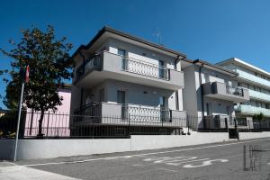 ein weißes Apartmenthaus mit Balkon auf einer Straße in der Unterkunft Du Lac Aparments in Desenzano del Garda