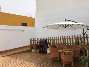 a patio with a table and a grill and an umbrella at Punta Brava Relax in Puerto de la Cruz