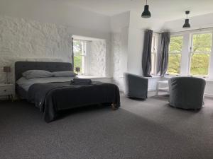 a bedroom with a bed and two chairs and windows at Hartfield House Hostel in Applecross