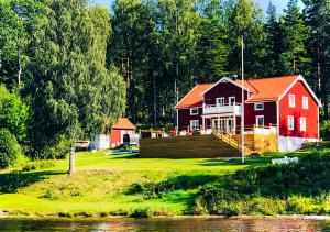 uma casa vermelha numa colina ao lado de um rio em Villa Fryksta em Kil