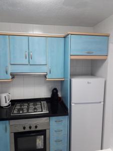 een keuken met blauwe kasten, een fornuis en een koelkast bij Apartamento Deluxe Yumbo in Playa del Inglés