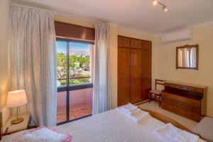 - une chambre avec un lit et une grande fenêtre dans l'établissement Apartamento São Pedro do Mar, à Quarteira