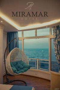 Miramar Boutique Hotel في الإسكندرية: كرسي الخوص يجلس أمام نافذة على سفينة