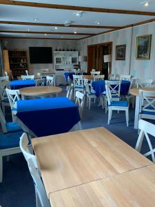 a dining room with tables and blue chairs at Flambards Hotel in Cardigan