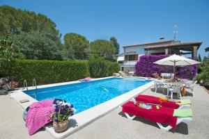 een zwembad met 2 stoelen en een parasol bij Villa ROTGER in Pollença