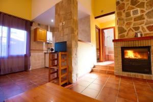 a living room with a fireplace and a kitchen at Aventura & Relax Cabañas Peña la Higuera in Villalba de la Sierra