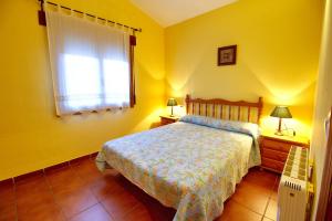 Dormitorio amarillo con cama y ventana en Aventura & Relax Cabañas Peña la Higuera en Villalba de la Sierra