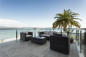 a patio with chairs and tables next to the water at Hotel Talaso Louxo La Toja in Isla de la Toja