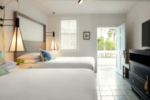 a bedroom with two beds and a tv and a window at Fitch Lodge - Key West Historic Inns in Key West