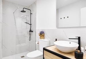 La salle de bains est pourvue d'un lavabo blanc et d'une douche. dans l'établissement Conde Alcalá Centro Parking Gratuito, à Grenade