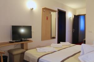a hotel room with two beds and a flat screen tv at Hotel Carpați in Predeal