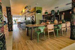 a dining room with a wooden table and green chairs at Live Hotels Bordeaux Lac in Bordeaux