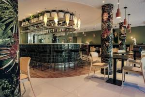 un restaurant avec un bar doté de chaises et de tables dans l'établissement Live Hotels Bordeaux Lac, à Bordeaux