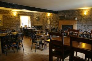 a restaurant with wooden tables and chairs and a fireplace at Bankfoot Inn in Bankfoot