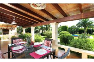 eine Terrasse mit einem Tisch und Stühlen unter einer hölzernen Pergola in der Unterkunft Villa MORENO in Pollença